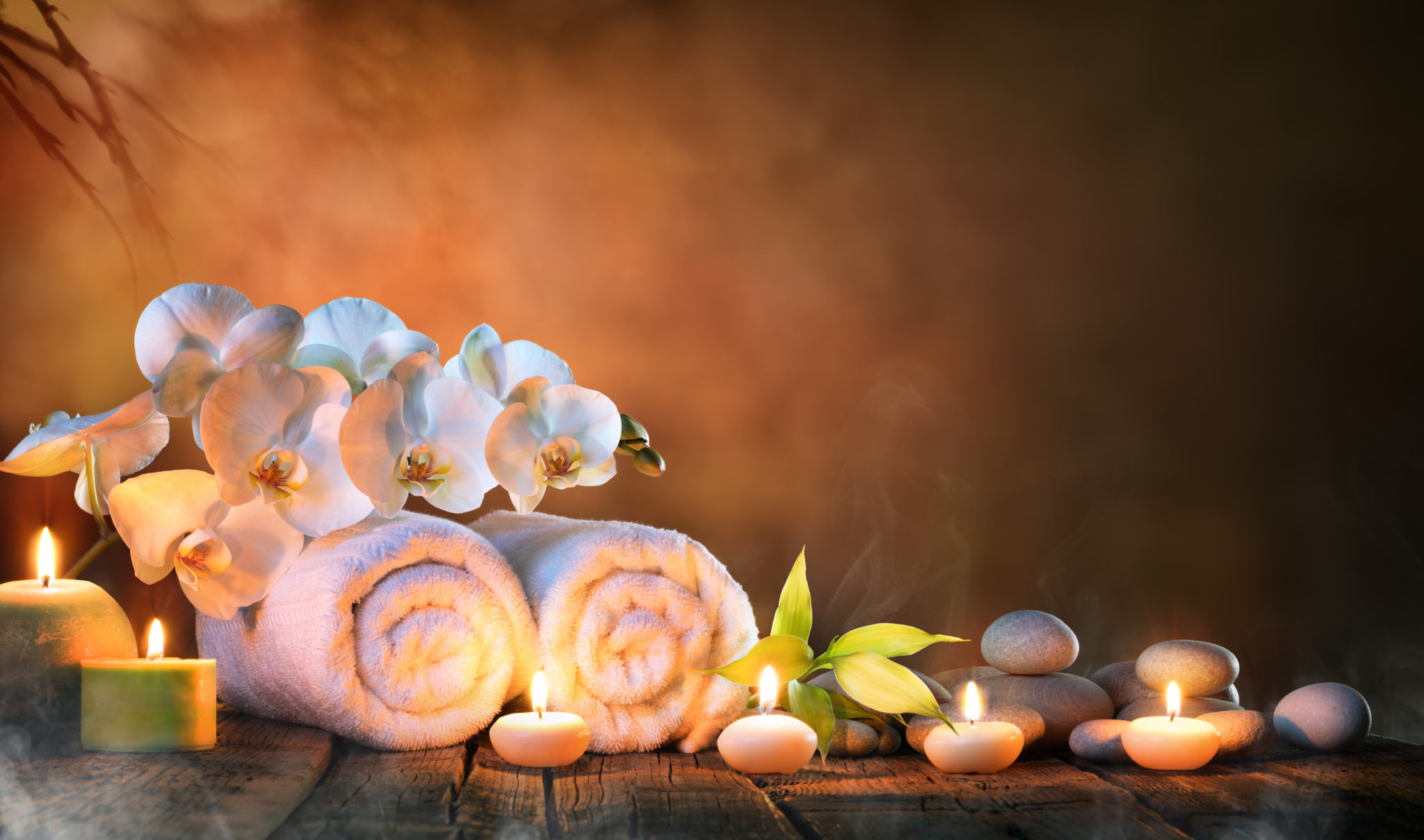 Spa - Couple Towels With Candles And Orchid For Natural Massage Two rolled towels flanked by lit candles and a white flower