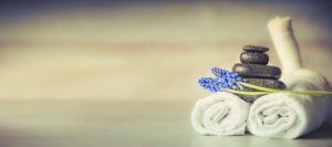 Pile of smooth pebbles and a sprig of lavender placed on top of two rolled towels